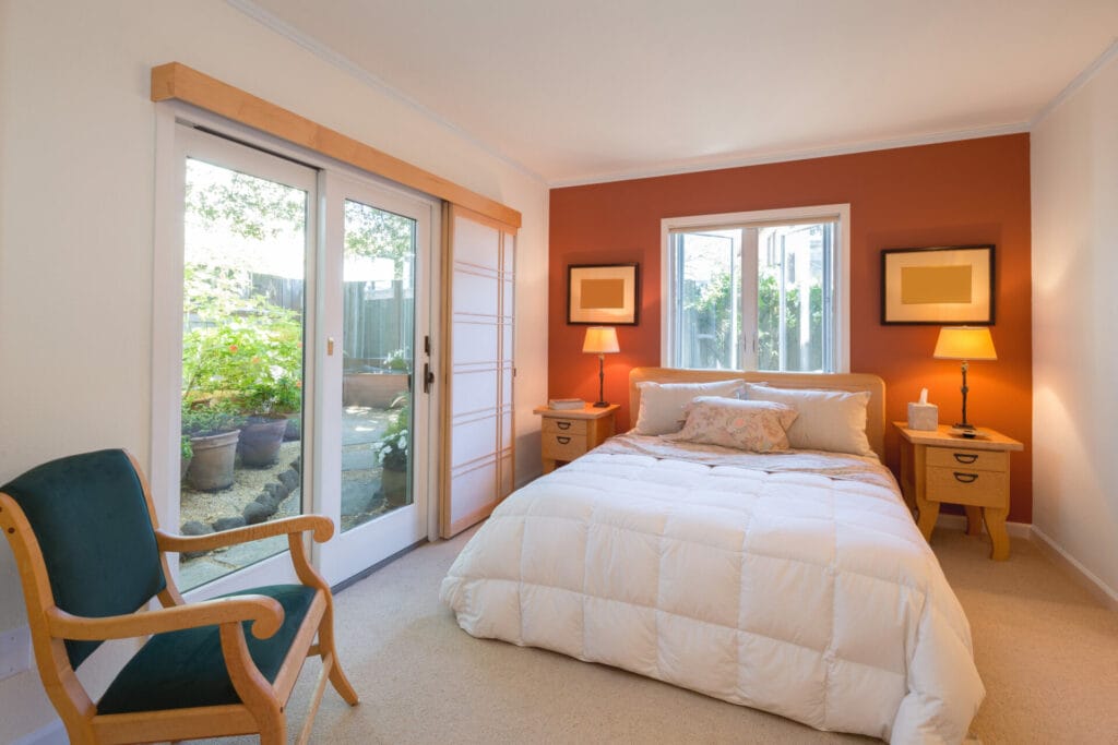 interior modern bedroom with orange accent wall and french doors