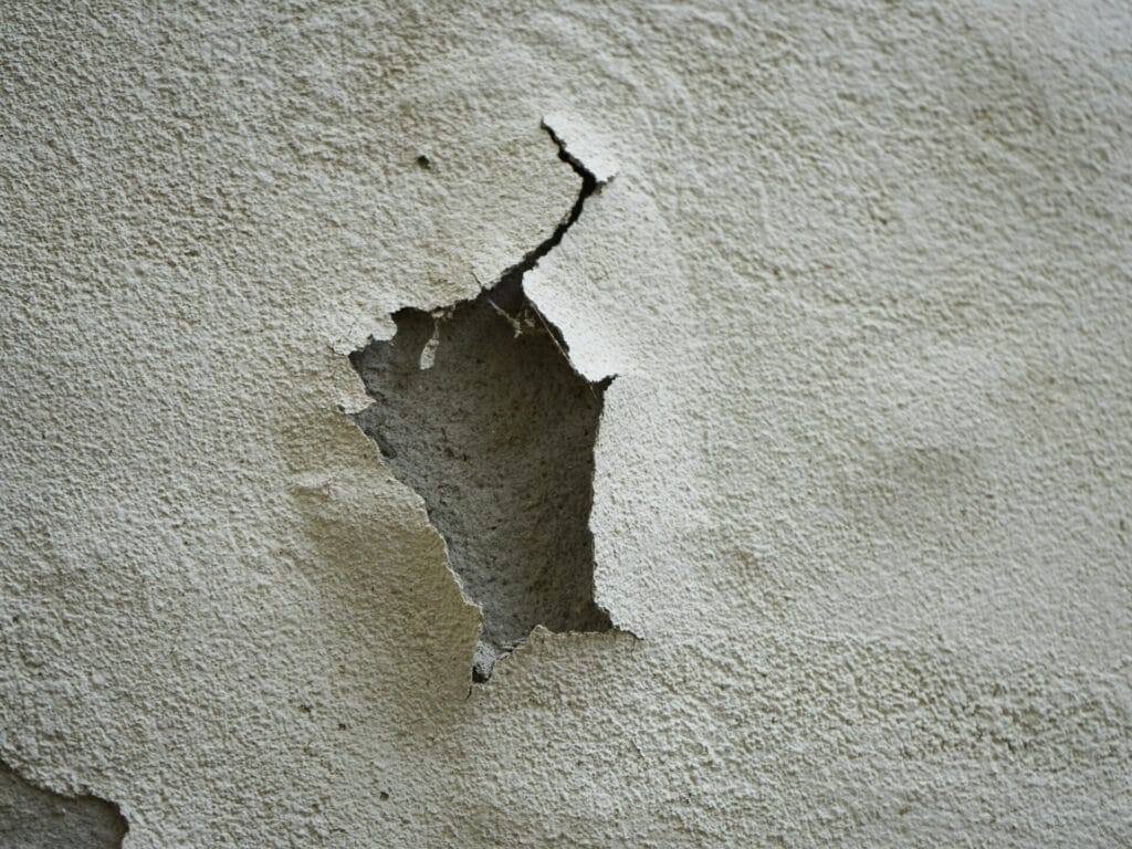 A closeup of a cracked white paint on the concrete wall