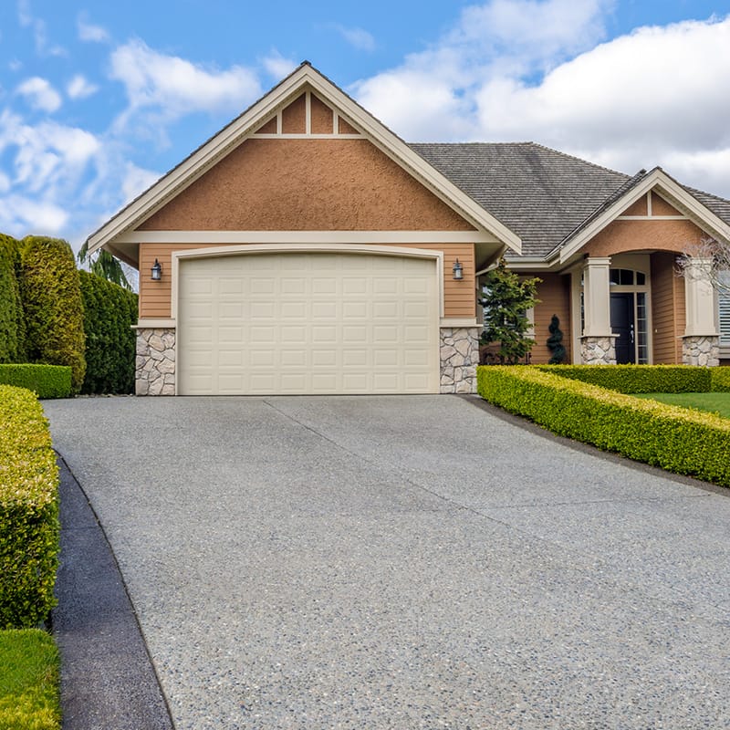 luxury house with a clean driveway and beautiful landscaping on a sunny day